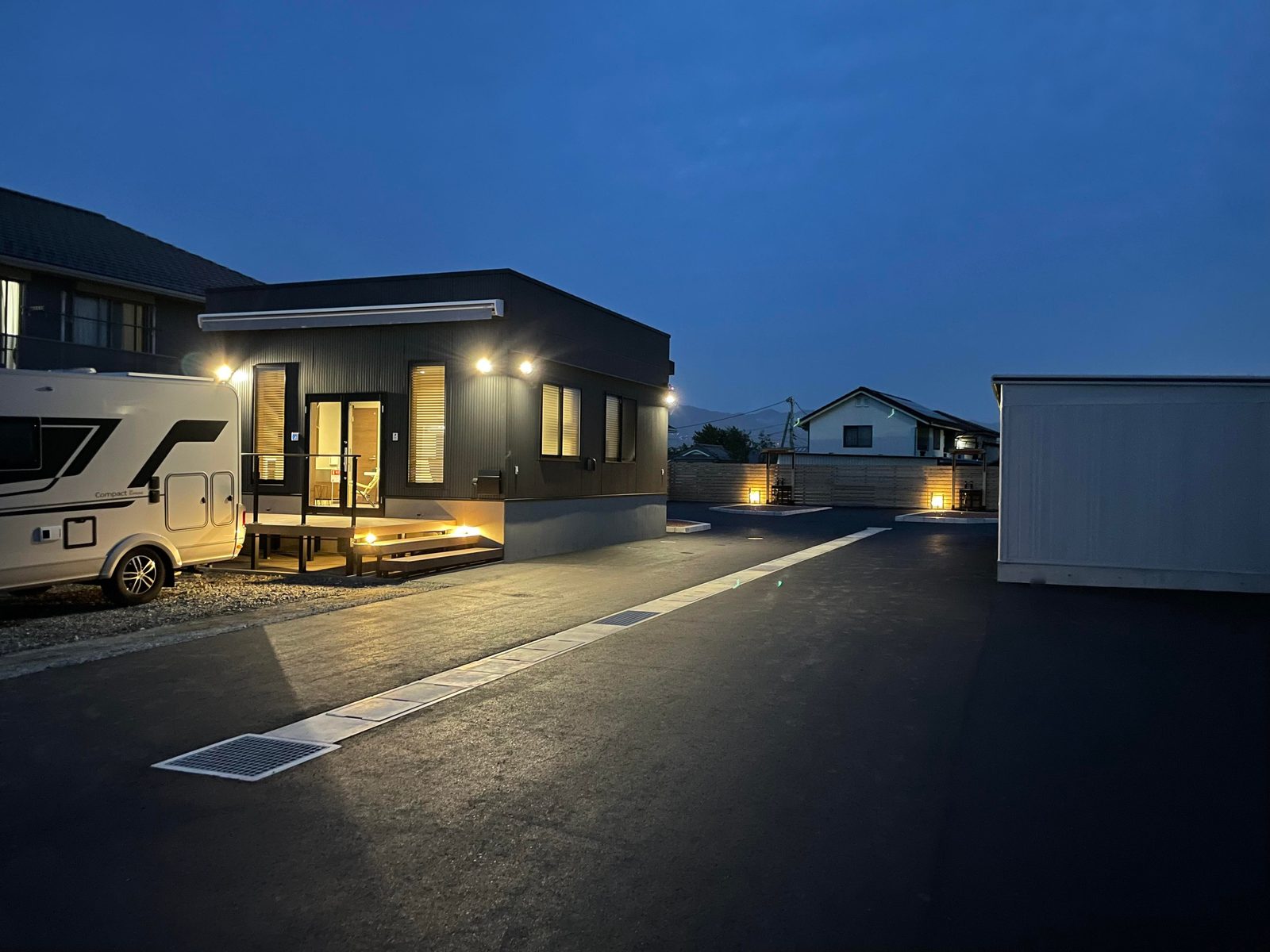 夕暮れの全景。管理棟の灯りとキャンピングカー