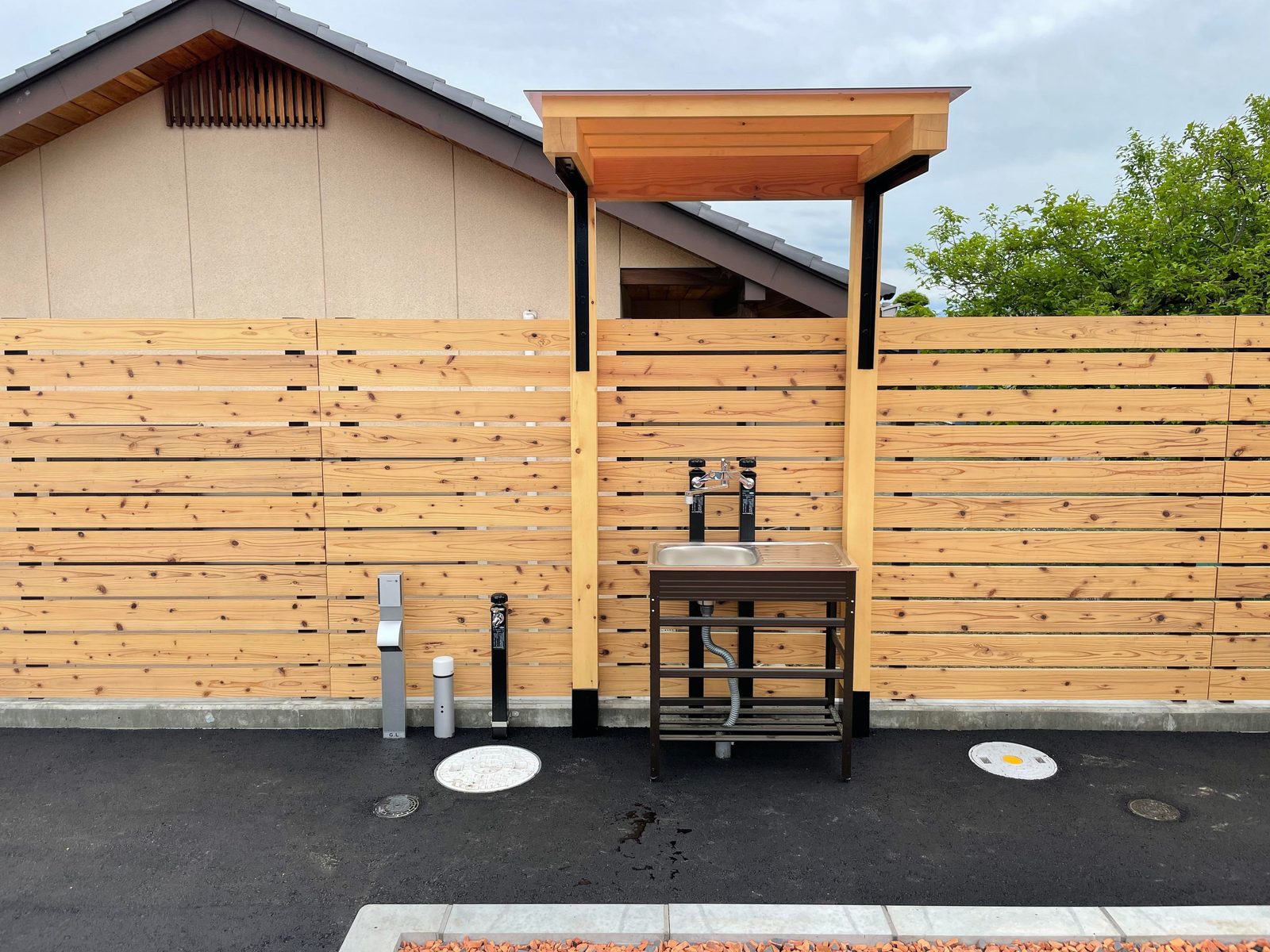 木塀の前に立つ屋外の手洗い場