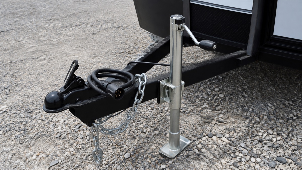 トレーラーの牽引ヒッチまわり。カプラー、ジャッキ、安全チェーン、電気コネクタが見える