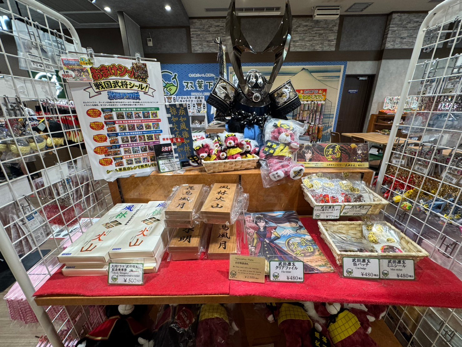 黒い甲冑を中心に武田菱丸のぬいぐるみや風林火山の木札が並ぶ売り場