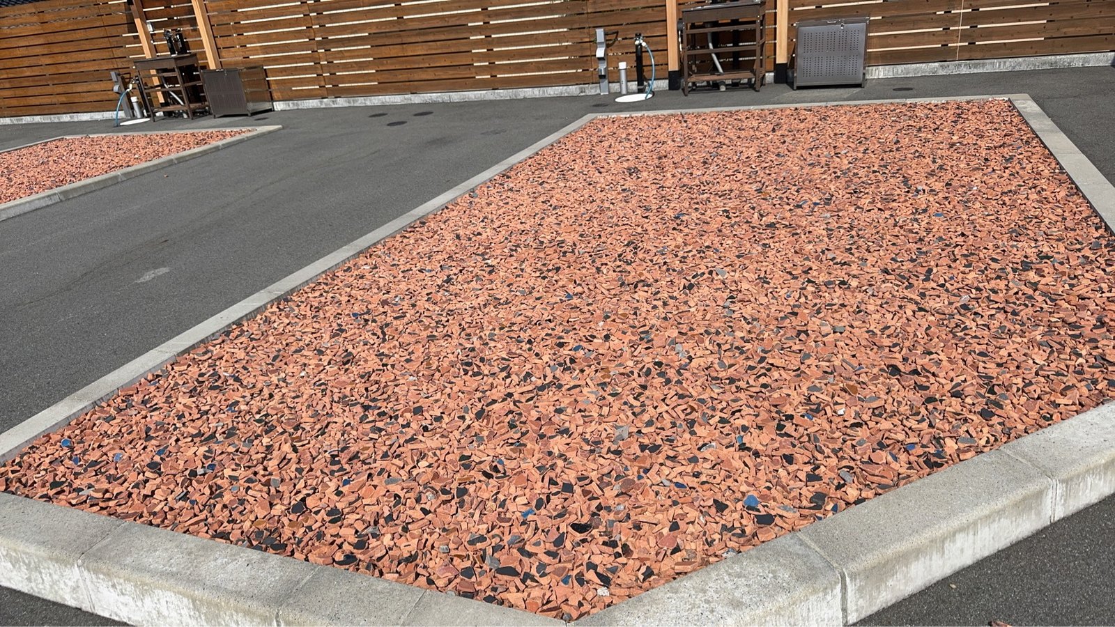 縁石で囲まれた赤茶色の瓦チップと各区画の水まわり設備