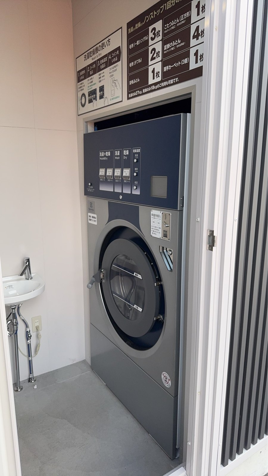 専用の小部屋に設置された大型のコイン式洗濯乾燥機