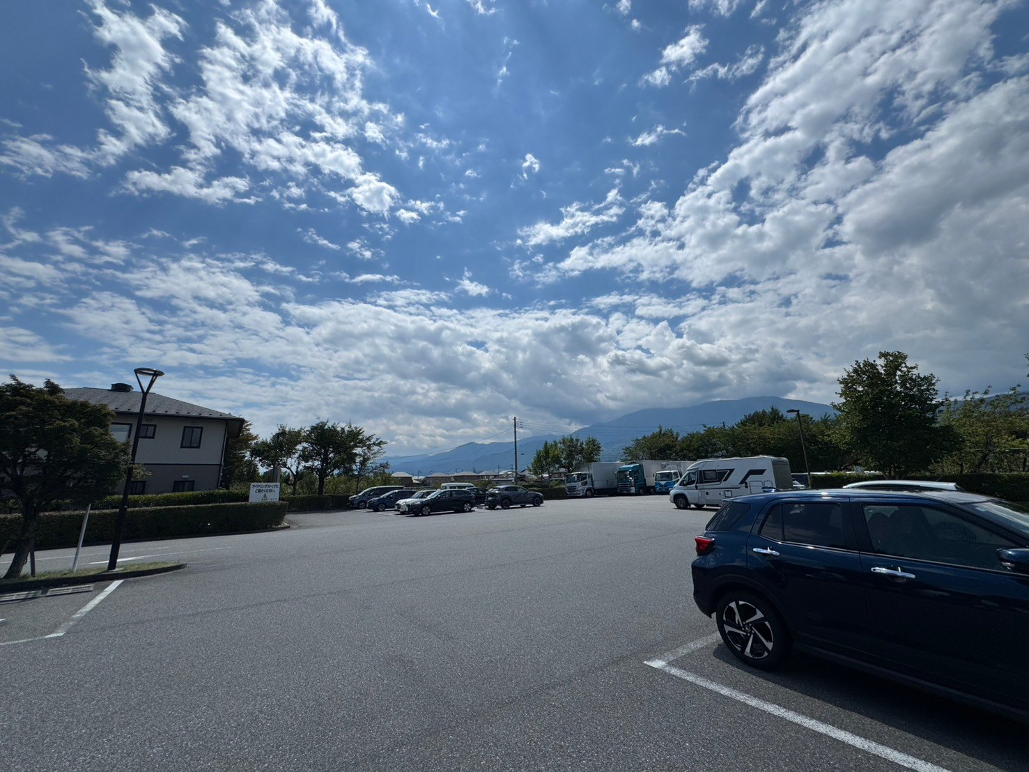 山並みを望む道の駅しらねの駐車場と駐車中の車