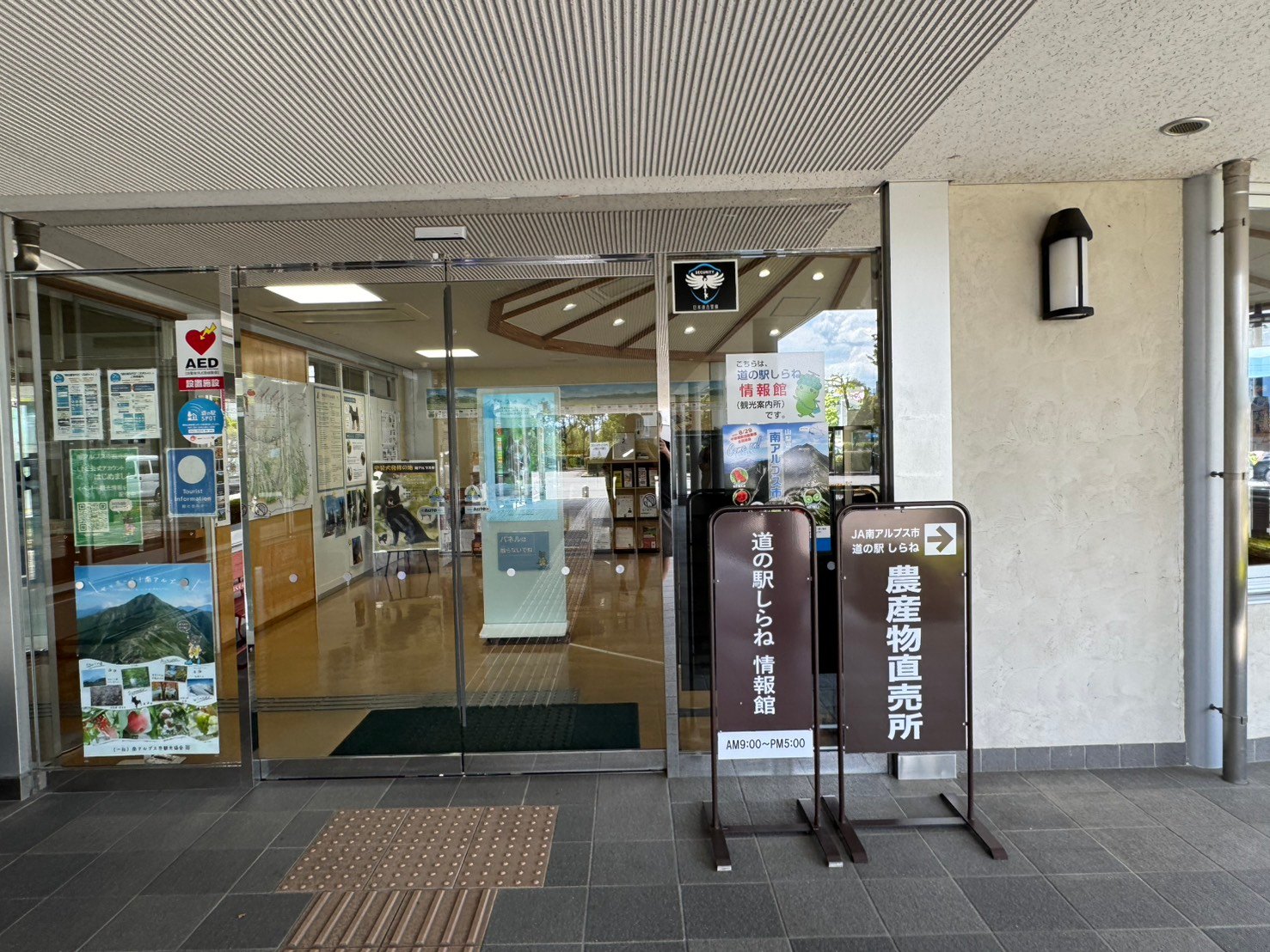 道の駅しらね情報館のガラス張りの入口と農産物直売所への案内板