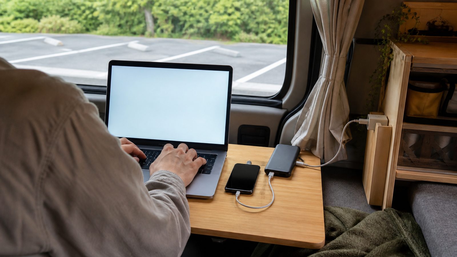 商業施設の駐車場に停まる小型バンとノートPC(イメージ)