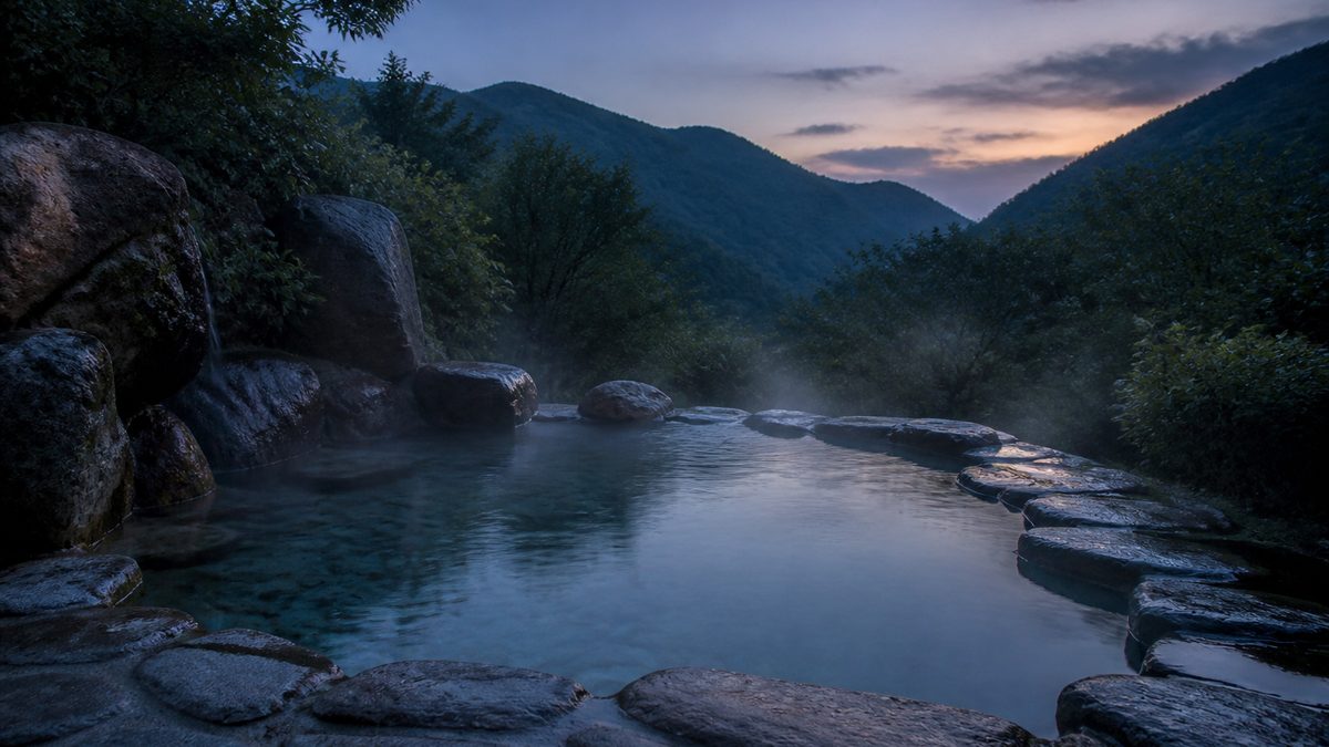 温泉の露天風呂をイメージした湯船と山の緑(イメージ)