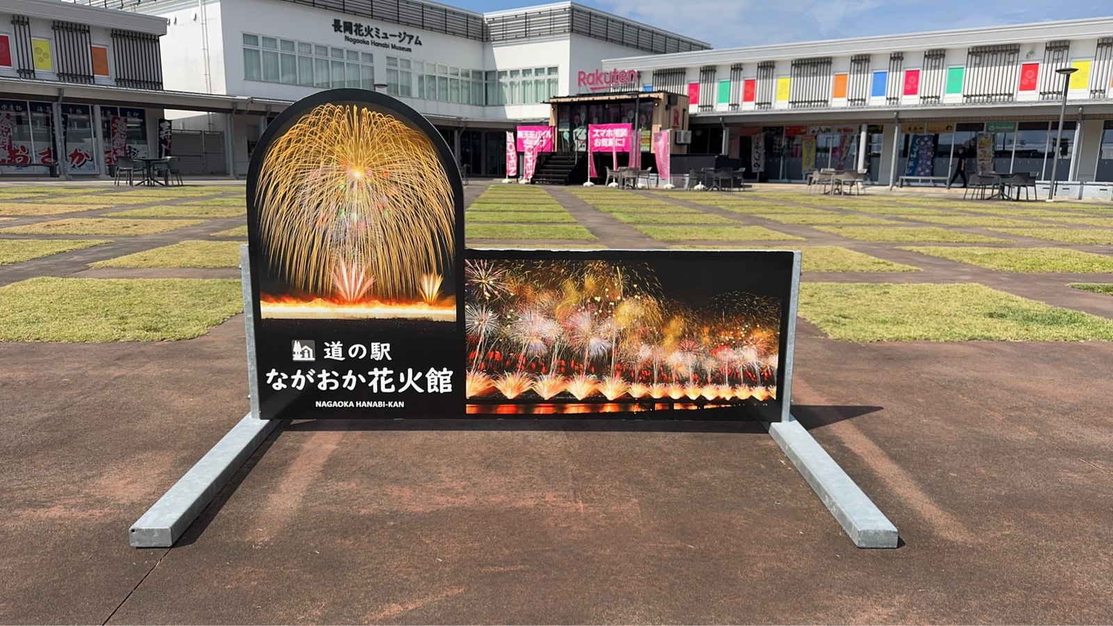 「道の駅 ながおか花火館」のフォトパネルと長岡花火ミュージアムの建物、芝生の広場