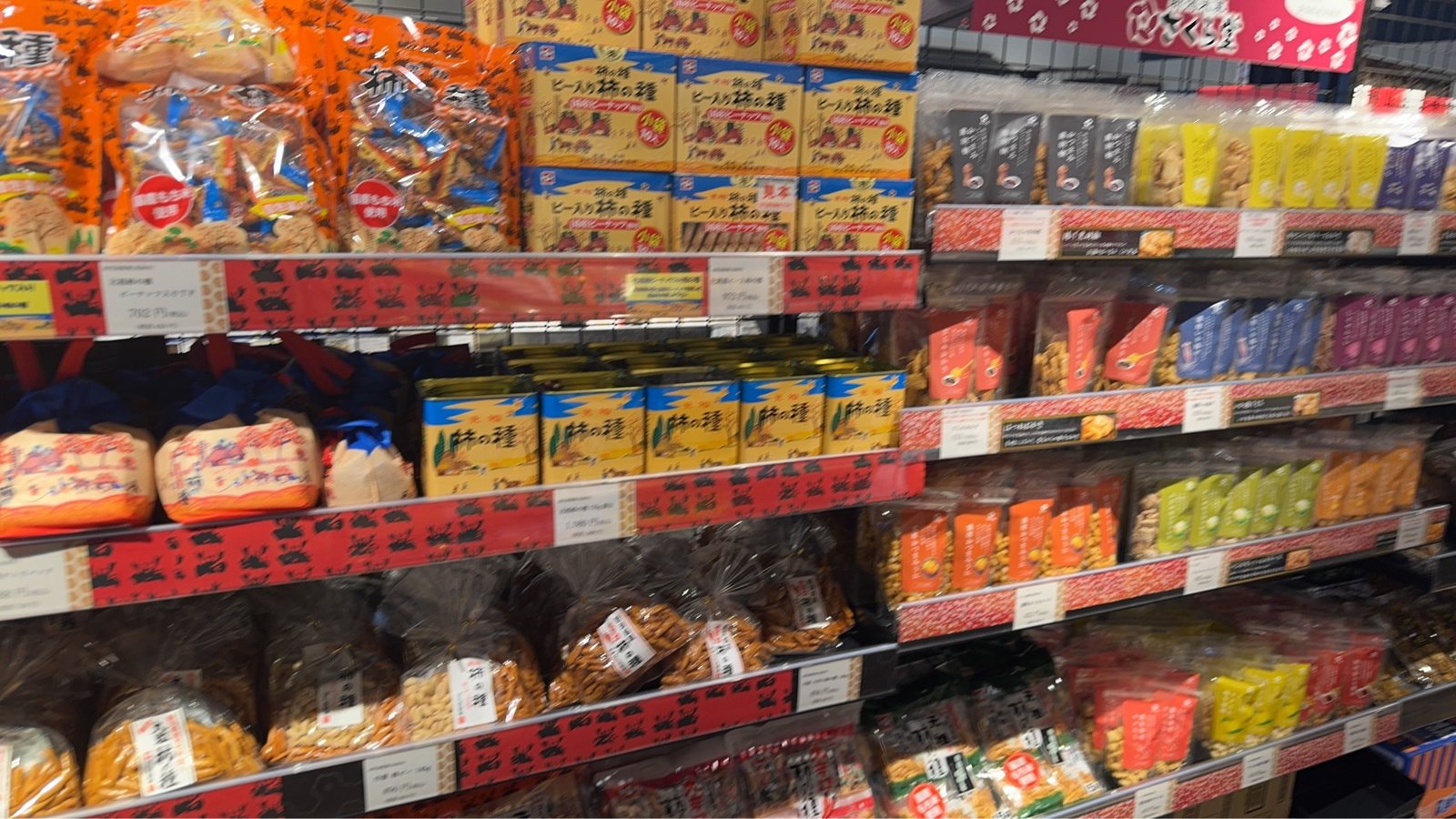 缶や箱、袋入りなど何段にも柿の種が並ぶ棚