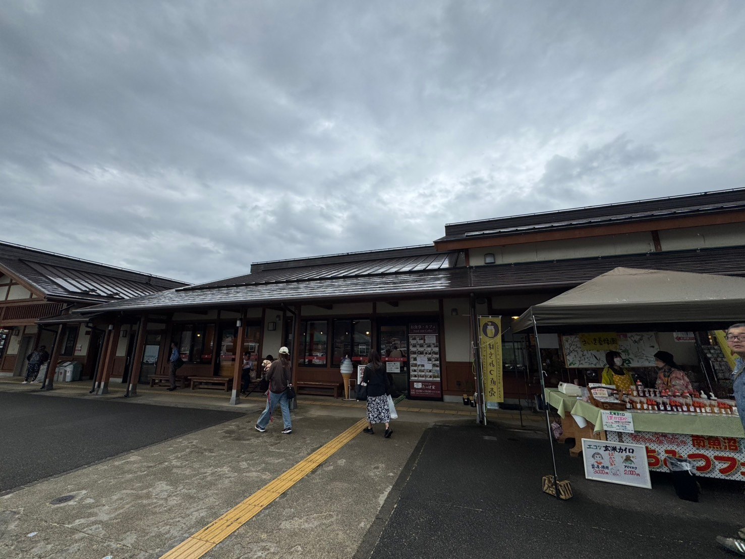 「お食事・カフェ」の入口とソフトクリームの模型がある建物正面。右に養蜂園のテント出店