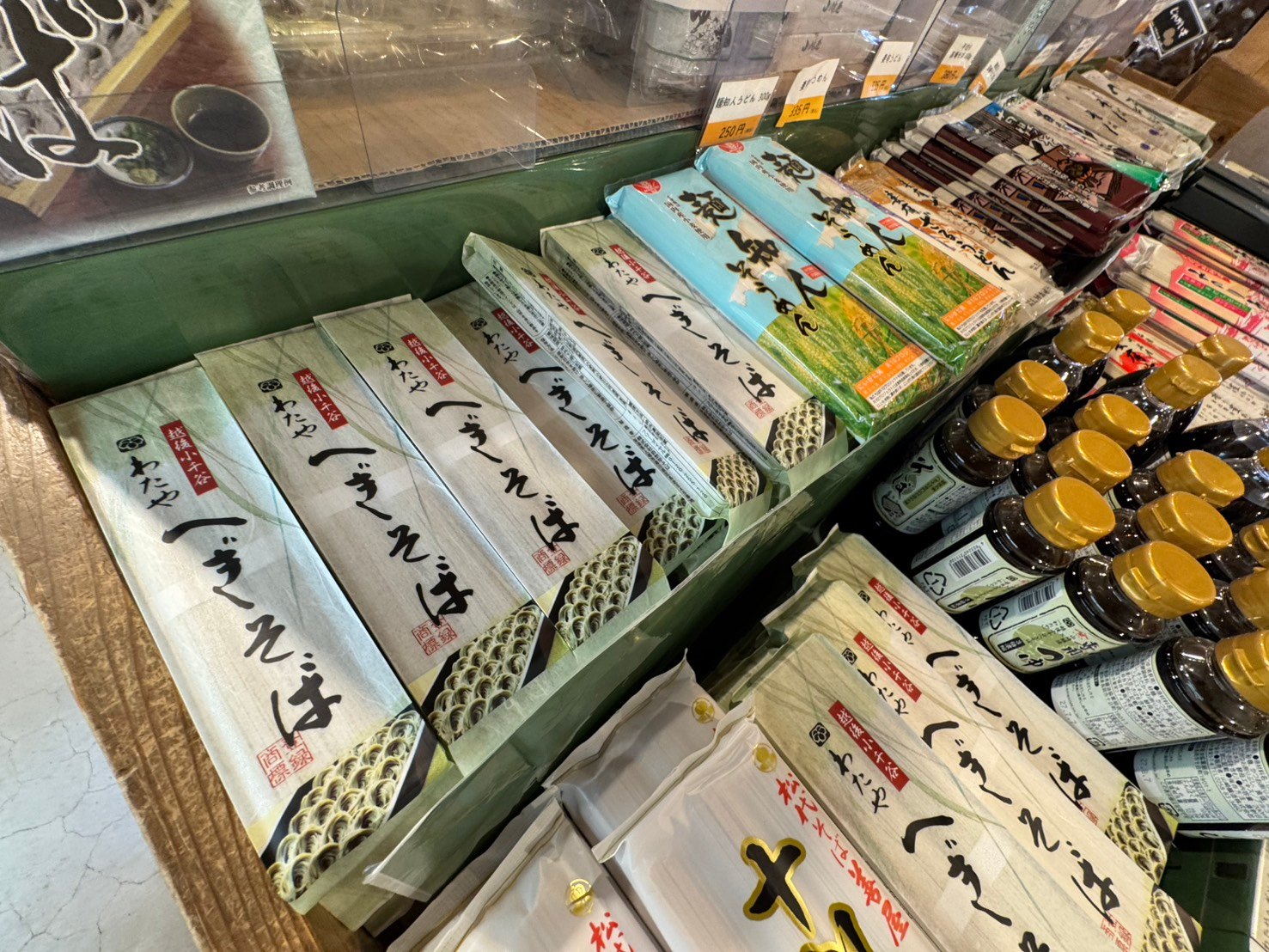 「わたや へぎそば」の乾麺がずらりと並ぶ棚。隣にそうめんや麺つゆの瓶も並ぶ