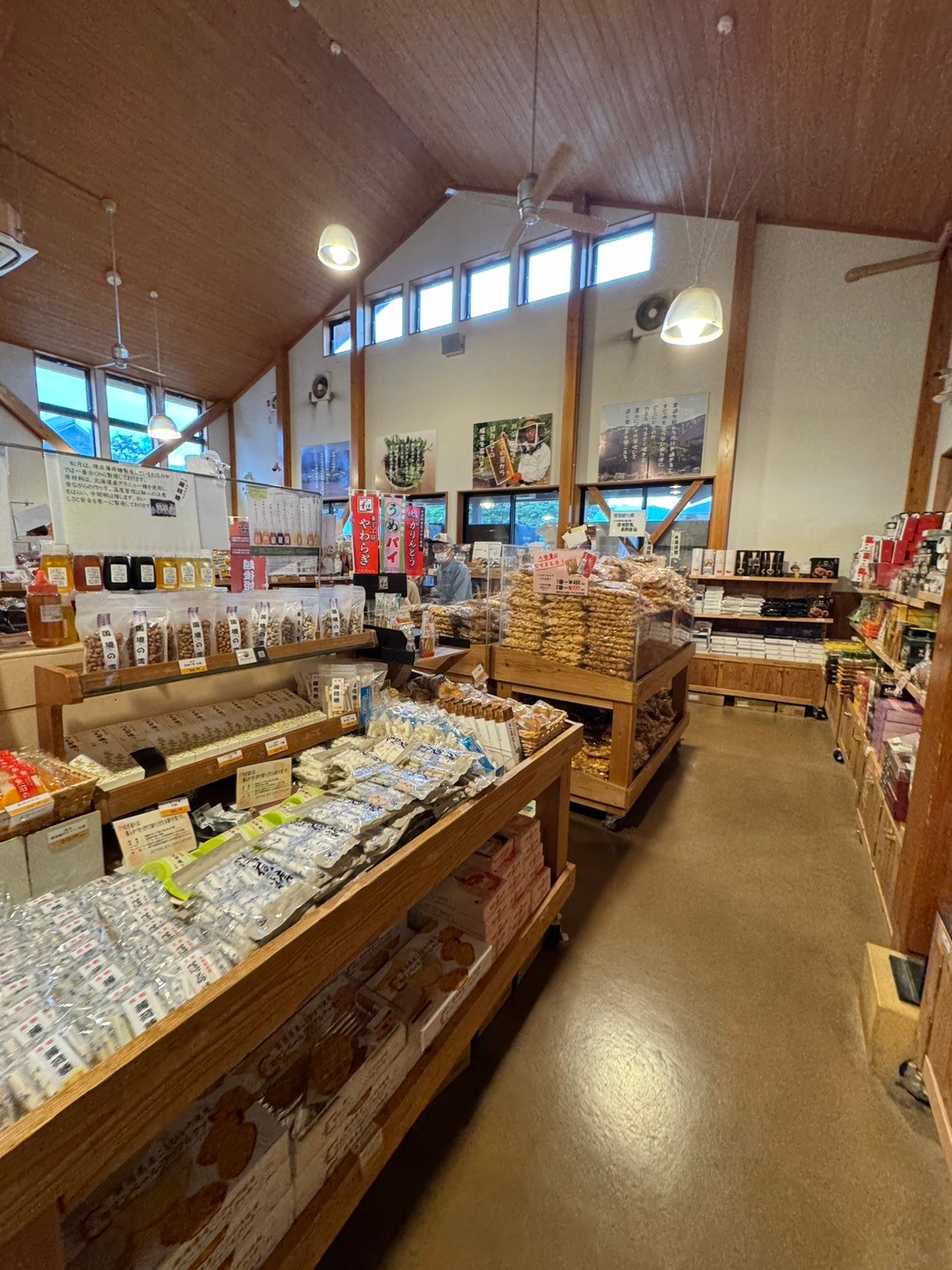 木の陳列台にはちみつやかりんとうが並ぶ売店の店内。高い板張りの天井