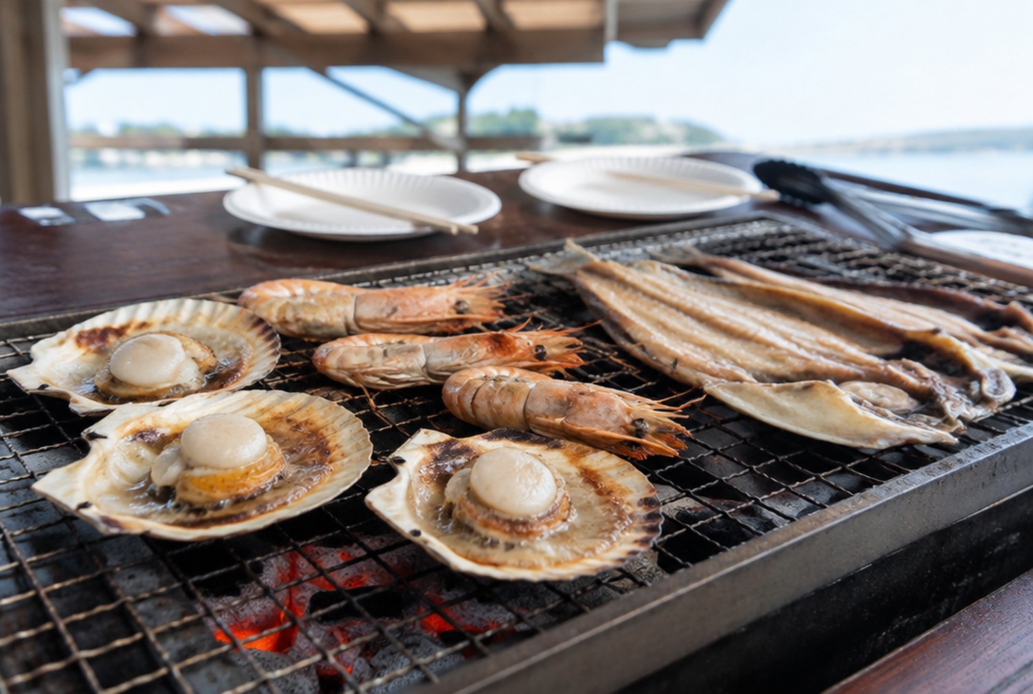 網の上でホタテやエビ、干物が焼けている屋外のバーベキュー席