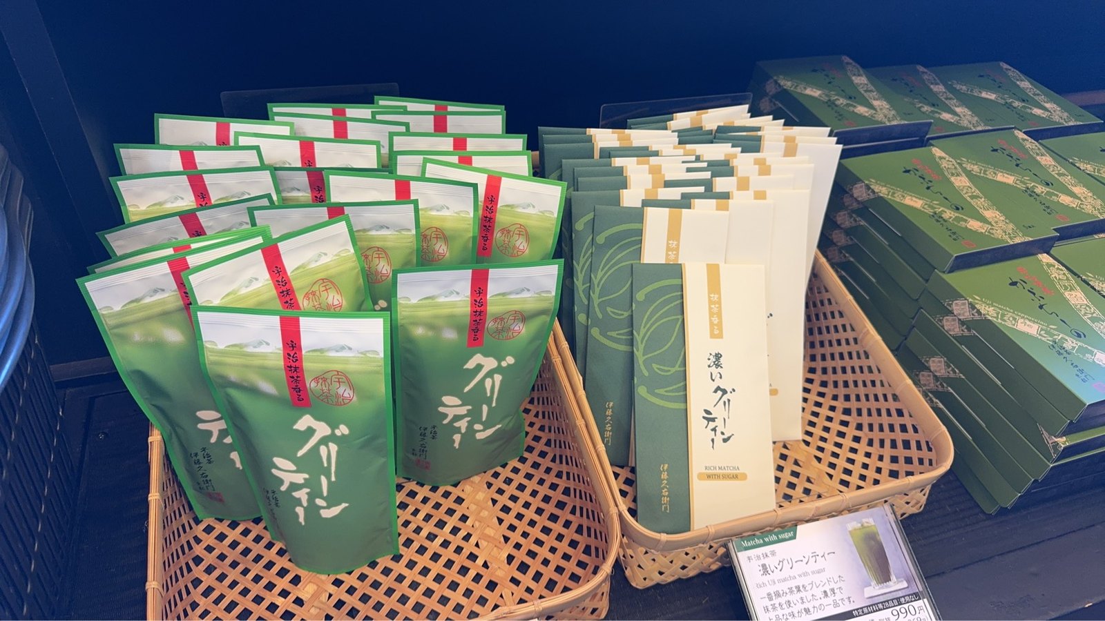 籠に並んだグリーンティーの袋と濃いグリーンティーの箱