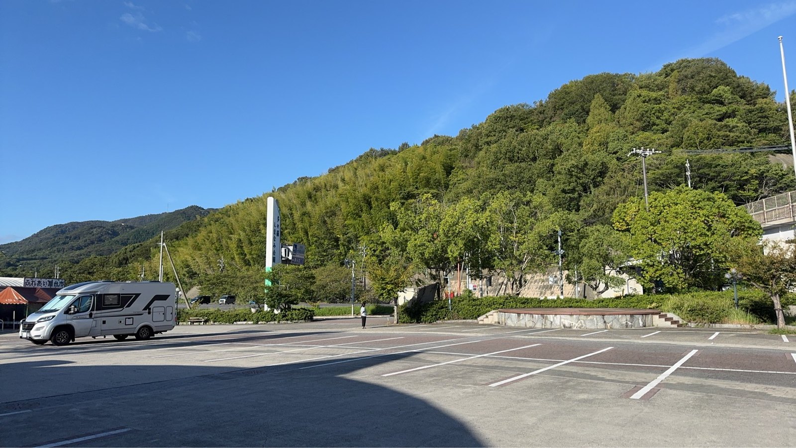 白線で区切られた多々羅しまなみ公園の駐車場とキャンピングカー、背後の緑の斜面