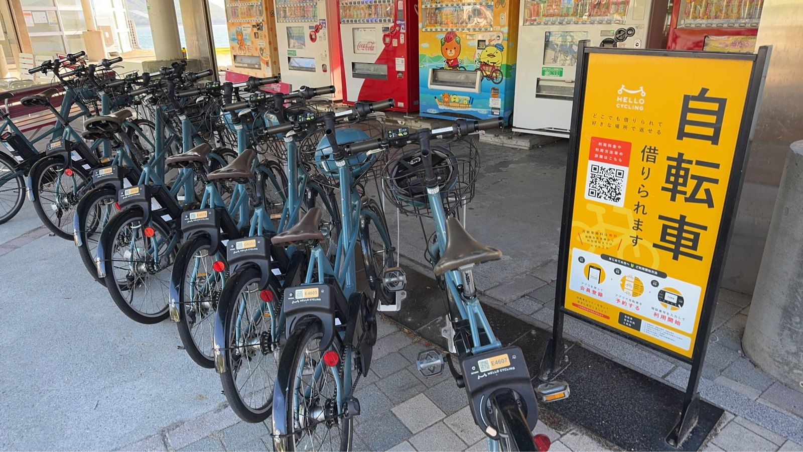 並んだHELLO CYCLINGの自転車と、会員登録や予約手順を示す黄色い案内看板