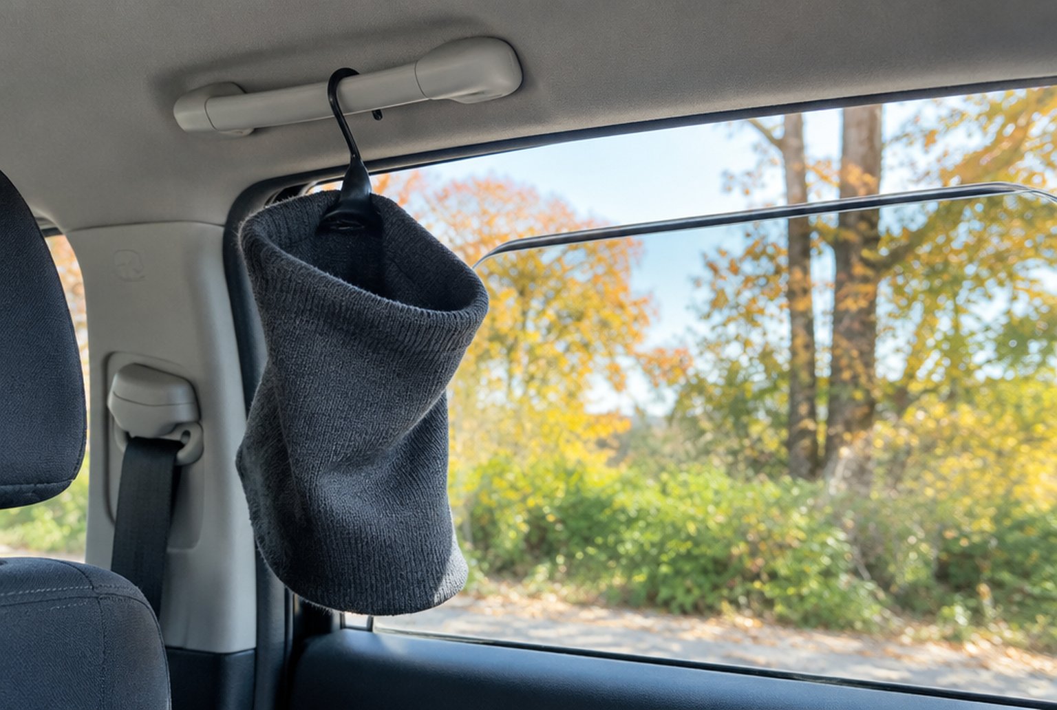 朝の車内、手すりに掛けたハンガーに無地のネックウォーマーが干してあり、少し開いた窓から朝の光が入っている。イメージ画像(AI生成。実際の商品の写真ではありません)