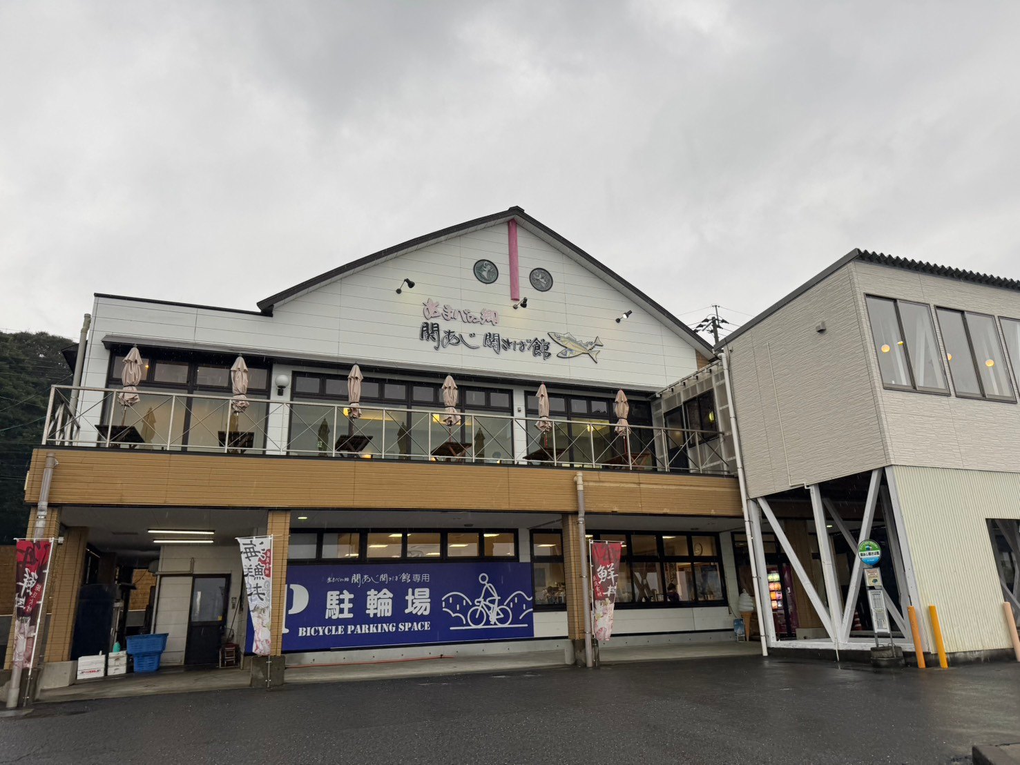 関あじ関さば館の建物正面と、2階のテラス、1階の駐輪場表示